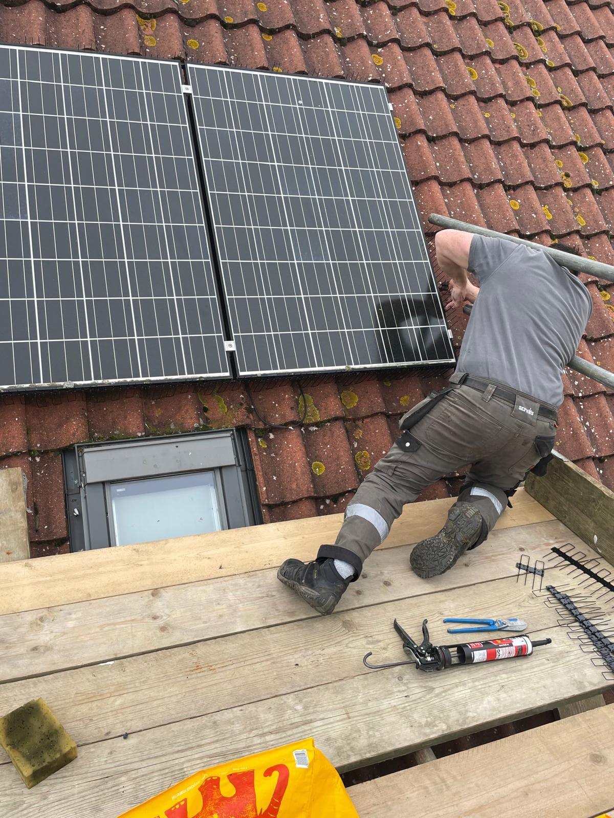 A Cinque Ports Pest Control technician fitting bird proofing to solar panels on a roof
